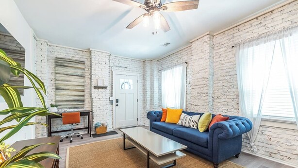 Ein Wohnzimmer mit blauem Sofa, einem Couchtisch, einem Deckenventilator und einer weißen Tür.