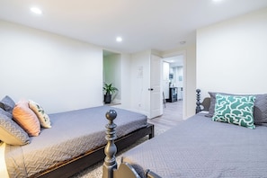 A bedroom with two beds, a potted plant, and a view into the kitchen. - 2 Blocks to Grant Park & Zoo | Firepit + Courtyard (Atlanta)