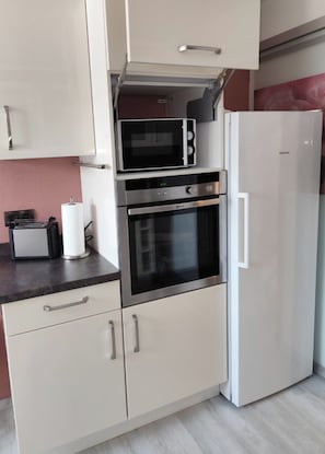 A compact kitchen with a microwave, oven, and refrigerator.