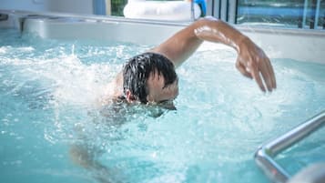 A person swimming in a pool with a clear view of the pool's edge and a window in the background.