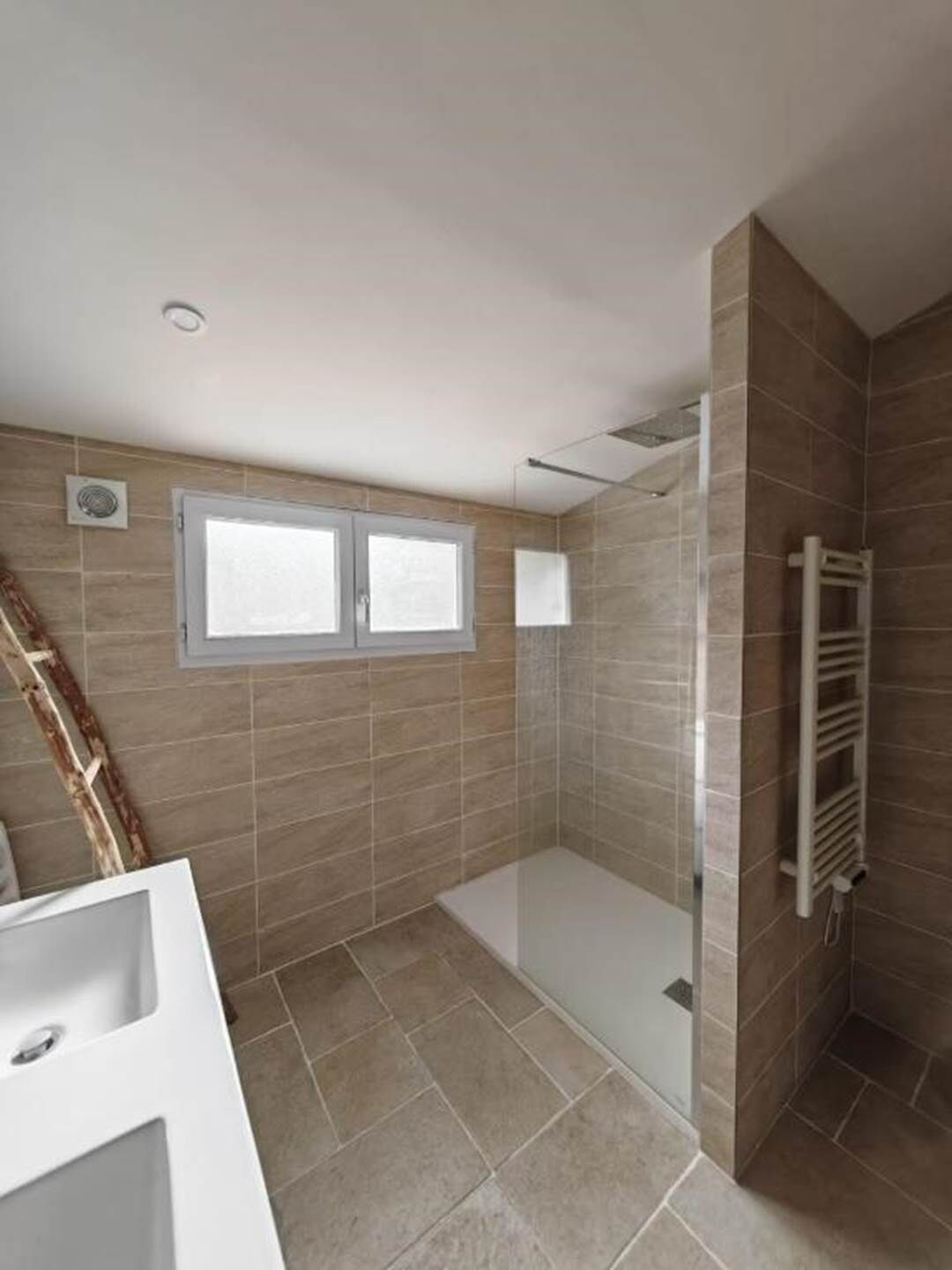 A modern bathroom with a shower, a window, and a towel rack.