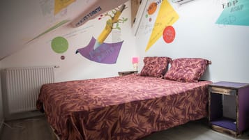 A bedroom with a bed, pillows, a nightstand, and a wall with various decorations.