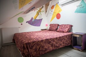 A bedroom with a bed, pillows, a nightstand, and a wall with various decorations.