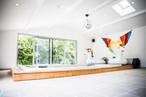 A spacious room with a large window, a wooden platform, and a ceiling light fixture.