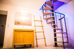 A wooden cabinet, a bamboo ladder, and a spiral staircase with a black metal frame and wooden steps.