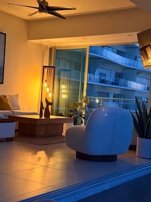A modern living room with a sofa, a coffee table, a floor lamp, and a large window with a view of a building. - Luxury 1-bedroom apartment at Icon Vallarta 2-801 with an ocean view (Puerto Vallarta)