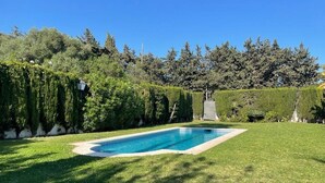 Una piscina rettangolare circondata da un prato curato e una fitta siepe.