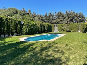 A rectangular swimming pool surrounded by a well-manicured lawn and dense shrubbery. - Studio Apartment 'Acogedor En La Playa' with Shared Pool, Wi-Fi and Air Conditioning (Marbella)