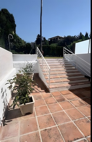 A set of outdoor stairs leading to a terrace with potted plants and a white railing. - Studio Apartment 'Acogedor En La Playa' with Shared Pool, Wi-Fi and Air Conditioning (Marbella)