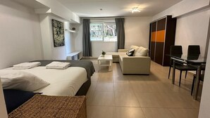Una camera d'hotel moderna con un letto, una poltrona, una scrivania e vista sul verde.