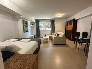 A modern hotel room with a bed, a sofa, a desk, and a view of greenery outside. - Studio Apartment 'Acogedor En La Playa' with Shared Pool, Wi-Fi and Air Conditioning (Marbella)
