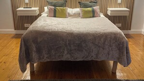 Quarto bem arrumado com cama, mesas de cabeceira e cabeceira.