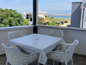 A balcony with a table and chairs, a view of the sea, and a building in the background. - Apartment Lavaran 4 (Vir)