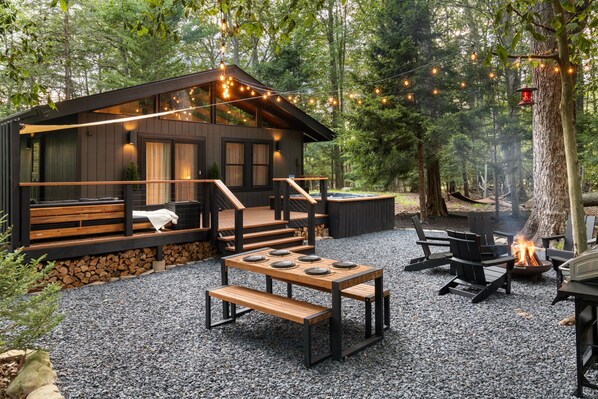 A cabin with a deck, outdoor seating, and a fire pit.