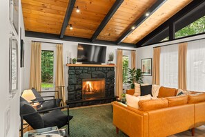 A cozy living room with a stone fireplace, a comfortable sofa, and a flat-screen TV mounted above the fireplace.