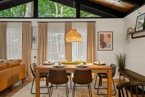 A dining area with a wooden table, chairs, and a hanging light fixture.