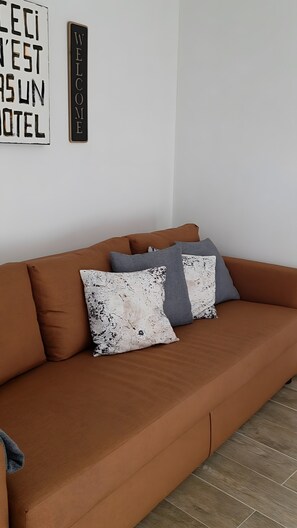 Un sofá marrón con dos almohadas estampadas y un letrero que dice 'WELCOME'.