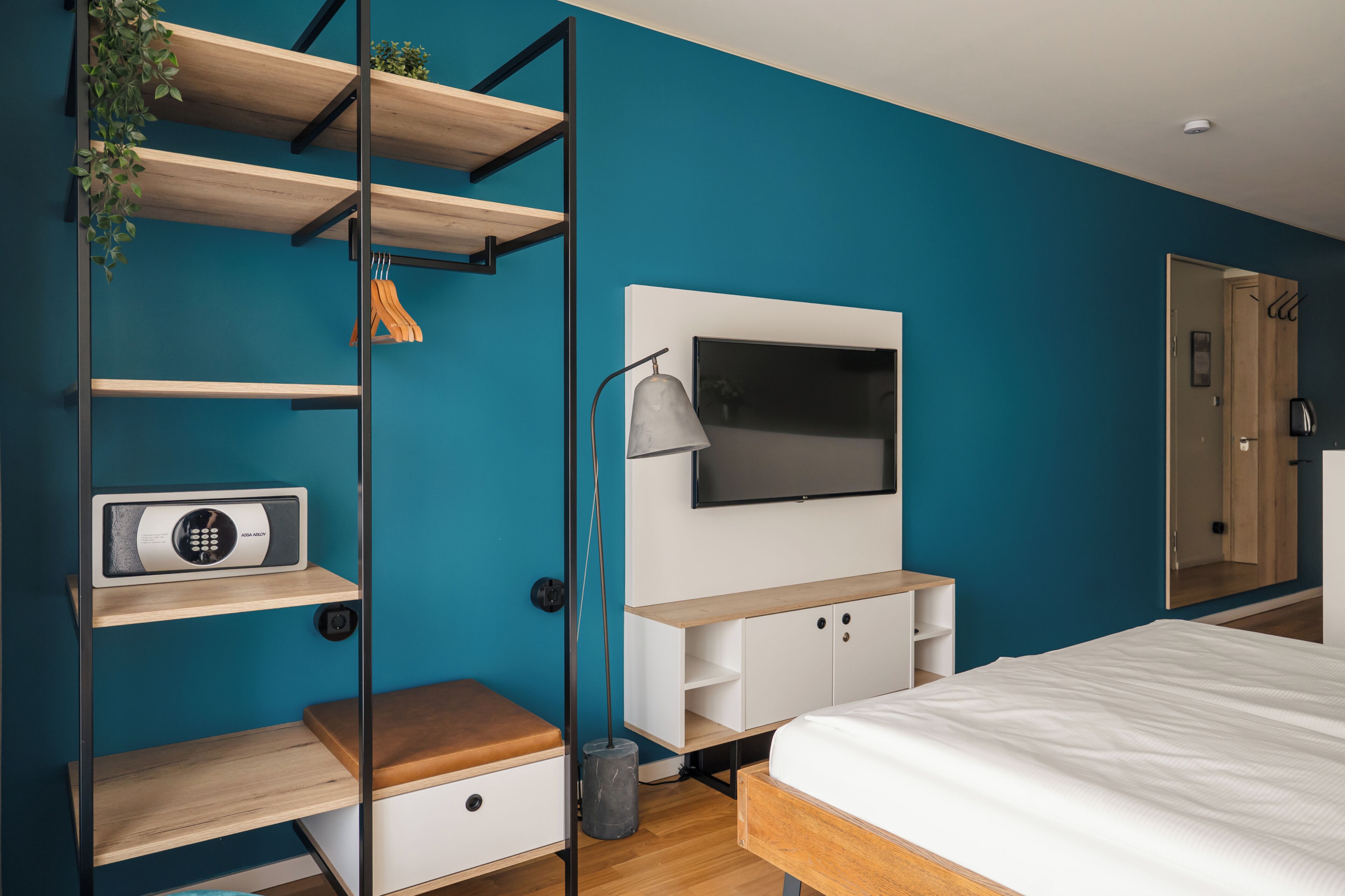 Un dormitorio moderno con televisor, estanterías de madera, cama y armario.