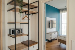 A modern room with a built-in shelving unit, a small radio, and a bed with a wooden headboard. - Homaris Tempelhofer Feld (Berlin)