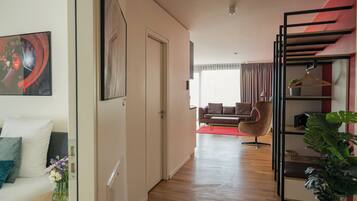 Una sala de estar moderna con un sofá, un tapete rojo, una silla colgante y una estantería.
