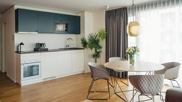 A modern kitchen with white cabinets, a built-in oven, and a microwave. There is a dining area with a round table and four chairs.