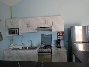 A compact kitchen with a microwave, stove, sink, and refrigerator.