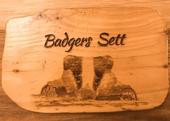 A wooden sign with the inscription 'Badgers Set' and a carved depiction of two rock formations. - Apartment Sleeps 4 With Parking (Blakeney)