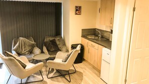 Een knus woongedeelte met een eethoek, een kitchenette en een deur naar een andere kamer.