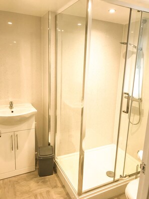 A modern bathroom with a glass-enclosed shower, a sink, and a toilet. - Apartment Sleeps 4 With Parking (Blakeney)