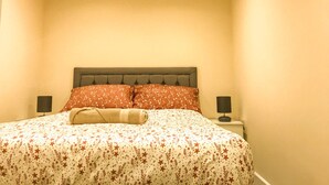 Een slaapkamer met een bed, twee nachtkastjes en een hoofdbord.