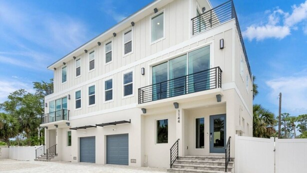 A two-story building with a flat roof, large windows, and a balcony on the upper floor.