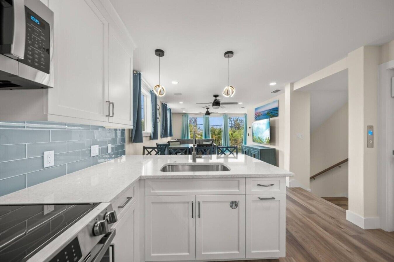 A modern kitchen with a central island, white cabinetry, and a black stove.
