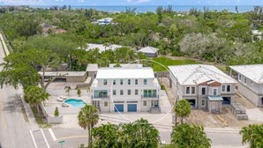 A residential property with a swimming pool, multiple buildings, and a view of the ocean.