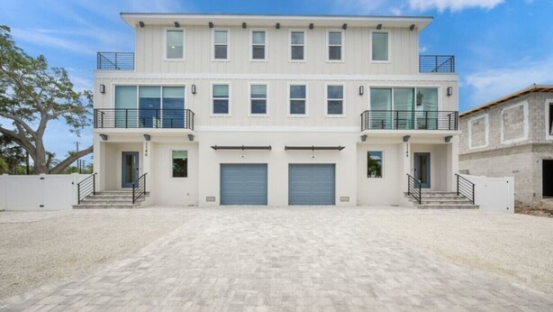 A two-story building with a flat roof, large garage doors, and a paved driveway.