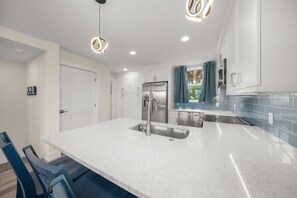 Una cocina moderna con armarios blancos, electrodomésticos de acero inoxidable y una isla grande con un lavamanos.