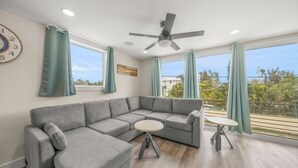 A modern living room with a grey sectional sofa, a small round table, and a ceiling fan.