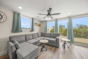 A modern living room with a grey sectional sofa, a small round table, and a ceiling fan.