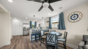 A modern kitchen with a central island, white cabinetry, and a ceiling fan.