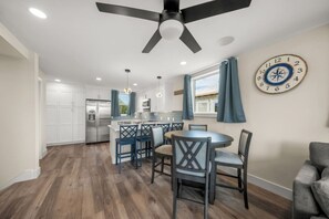 A modern kitchen with a central island, white cabinetry, and a ceiling fan.