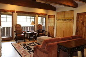 A cozy room with a wooden table, two chairs, a sofa, and a large window with blinds. - NEW! One Bedroom Two Queen Suite (Park City)