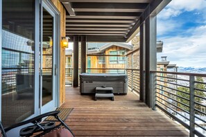 Eine Holzterrasse mit Whirlpool, einem kleinen Tisch und einem Stuhl.