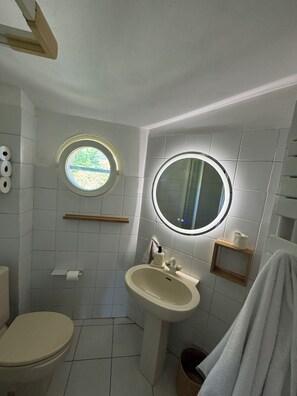 Ein Badezimmer mit Toilette, Waschbecken und zwei runden Spiegeln.