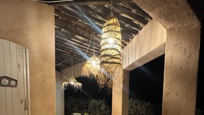 An outdoor patio with a round table and chairs, a hanging light fixture, and a door with a clock. - Welcome to Villa Sulvia, located between the sea and the hinterland of Provence. (Roquefort-les-Pins)