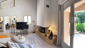 A spacious living area with a TV, seating, and a view of the outdoors. - Welcome to Villa Sulvia, located between the sea and the hinterland of Provence. (Roquefort-les-Pins)
