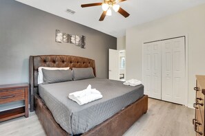 Ein Schlafzimmer mit einem großen Bett, einem Deckenventilator, einem Kleiderschrank und einem Nachttisch.