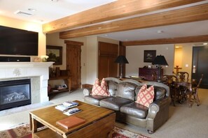 A cozy living room with a fireplace, leather sofa, wooden coffee table, and a television. - Upgraded Deluxe Mountain Studio (Park City)