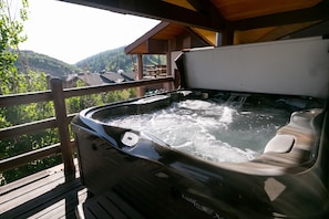 Un jacuzzi en una terraza de madera con vistas a un paisaje montañoso.