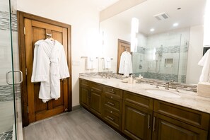 A modern bathroom with wooden cabinets, a large mirror, and a glass shower enclosure. - NEW! Bald Eagle Two Bedroom (Park City)