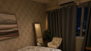 A bedroom with a bed, a chair, a mirror, and a window with curtains. - Hotel Comfort at Shell MOA - Near SMX & IKEA (Pasay City)