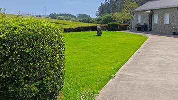 A rural property with a stone building, a paved driveway, and a well-maintained lawn.